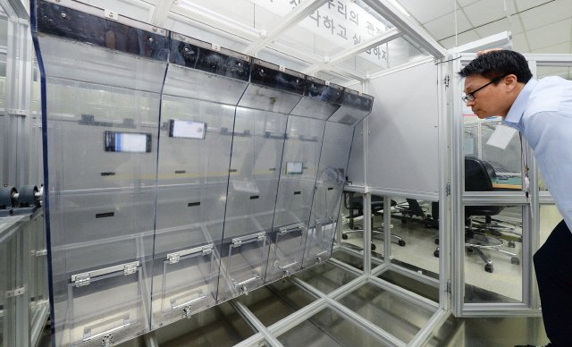  약 1미터 높이의 투명한 사각 통 안에 V20를 넣고 끊임없이 회전해 테스트를 진행하는 ‘연속 낙하 시험’ 장면. LG전자 연구원이 제품에 반복적인 충격을 가해 내구성에 이상이 없는지 검증하고 있다. 