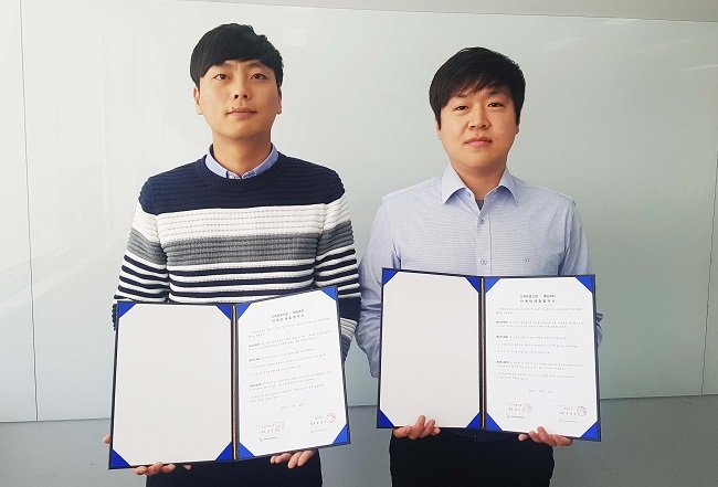 김일신 스마트포스팅 CMO(오른쪽)와 박기훈 게임코치 제작본부장(왼쪽)이 협약서에 서명을 하고 포즈를 취하고 있다.
