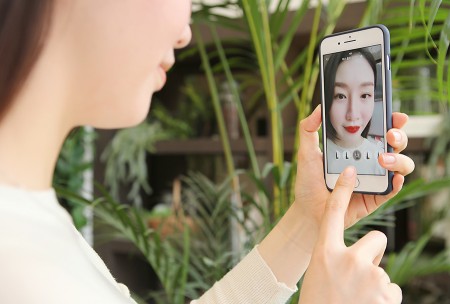 한 고객이 더현대닷컴 앱을 이용해 AR 메이크업 서비스를 이용해 가상으로 립스틱을 발라보고 있다. 사진=현대백화점 제공