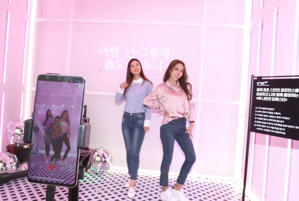 서울 강남역 인근에 마련된 U+5G 팝업스토어 ‘일상로5G길’에서 LG유플러스 모델들이 TV속 스타를 불러내 함께 춤을 추며 영상을 찍을 수 있는 'U+AR'을 즐기고 있다 [사진=LG유플러스]