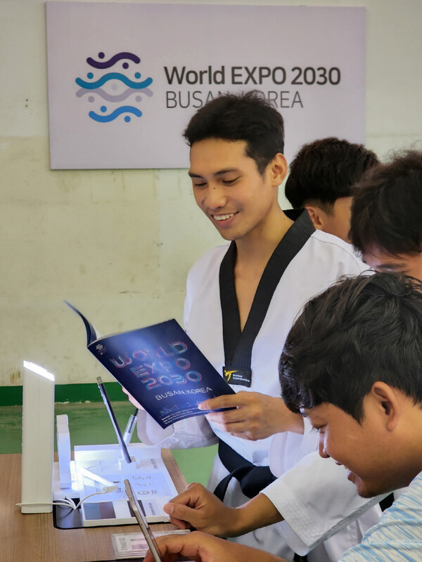 대회에 참가한 캄보디아 청소년 선수들이 스마트폰, TV 등 삼성전자 제품을 체험하고 부산엑스포 안내 책자를 살펴보고 있다.